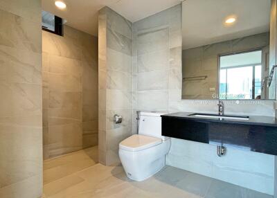 Modern bathroom with toilet, shower, large mirror, and sleek vanity
