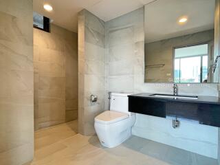 Modern bathroom with toilet, shower, large mirror, and sleek vanity