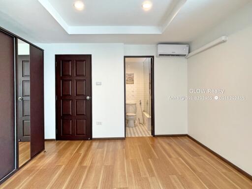 Spacious modern bedroom with wooden floor, built-in wardrobe, and en-suite bathroom