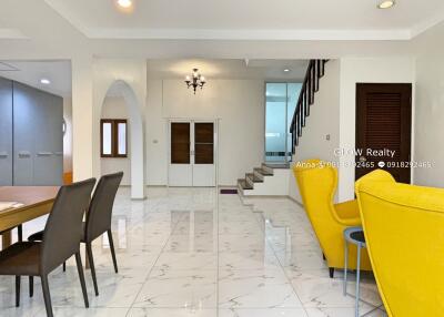 Spacious and modern main living area with dining table, chairs, staircase and armchairs