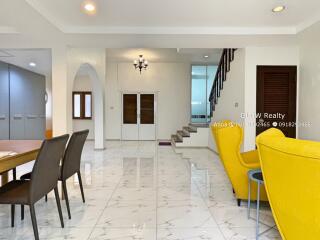 Spacious and modern main living area with dining table, chairs, staircase and armchairs