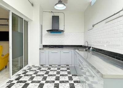 Modern kitchen with checkered floor, white tile backsplash, and stainless steel sink