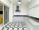 Modern kitchen with checkered floor, white tile backsplash, and stainless steel sink