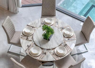 Elegant dining table set for six with a centerpiece, overlooking a pool