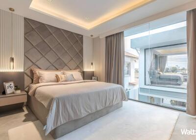 Modern bedroom with a large bed, decorative headboard, bedside tables, and a large window