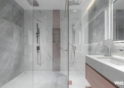 Modern bathroom with a glass shower, marble walls, and a vanity sink