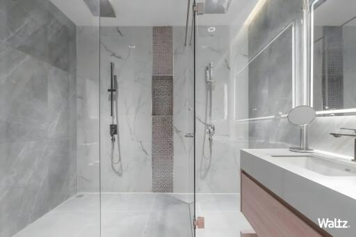 Modern bathroom with a glass shower, marble walls, and a vanity sink