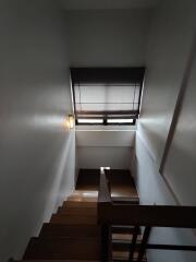 Interior staircase with wooden steps and a window with blinds