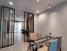 Modern dining room with glass table and beige chairs, view into living area