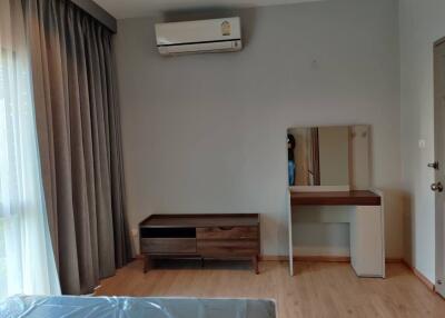 Bedroom with air conditioner, window with curtains, small desk with mirror, and wooden cabinet