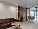 Modern living room with built-in wooden shelves, brown sofa, and adjoining dining area