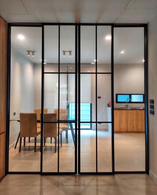 Modern dining room with glass partition and view into kitchen