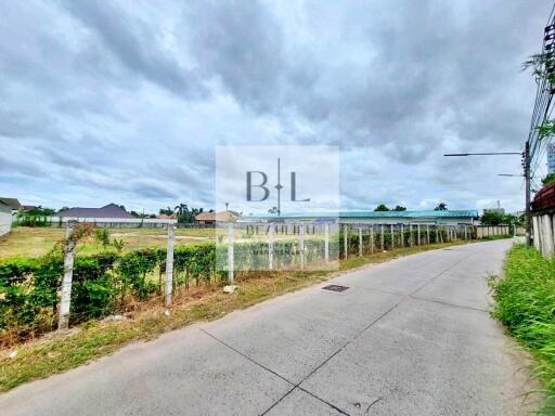 View of the surrounding neighborhood with a concrete road and green fencing