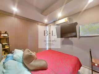 Bedroom with red bedspread, TV, and wall art