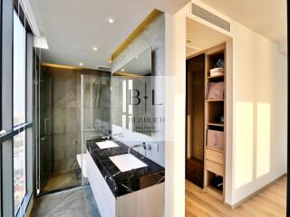 Well-lit modern bathroom with dual sinks and walk-in shower