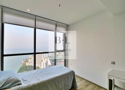 Minimalist bedroom with large window offering ocean view