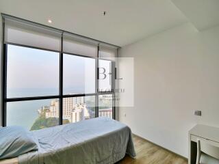 Minimalist bedroom with large window offering ocean view
