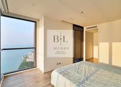 Modern bedroom with ocean view, hardwood floors, and large windows