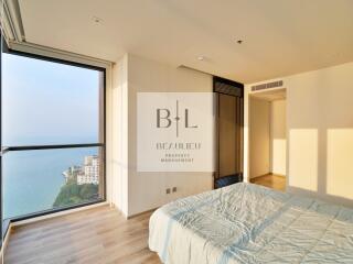 Modern bedroom with ocean view, hardwood floors, and large windows