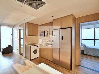 Modern apartment unit with a fully equipped kitchen and a view into the bedroom