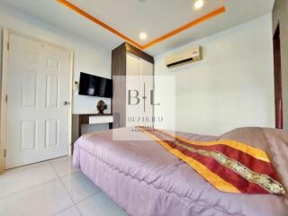 Modern bedroom with bed, wall-mounted TV, air conditioner, and wardrobe