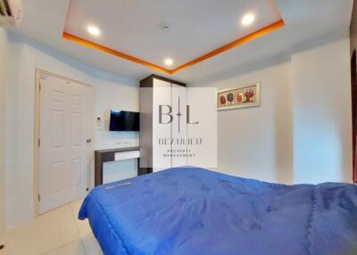 Modern bedroom with blue bedding, a wall-mounted TV, and a decorative ceiling