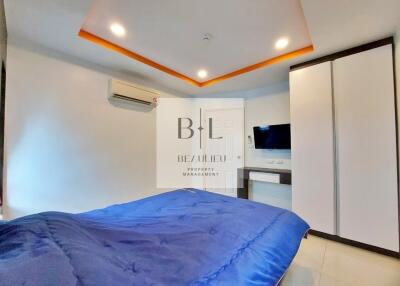Modern bedroom with blue bedspread, air conditioning, wardrobe, and wall-mounted TV