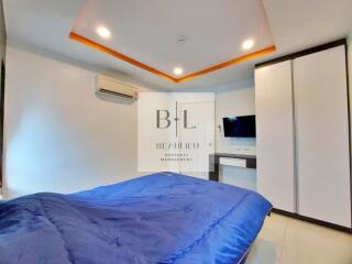 Modern bedroom with blue bedspread, air conditioning, wardrobe, and wall-mounted TV