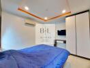 Modern bedroom with blue bedspread, air conditioning, wardrobe, and wall-mounted TV