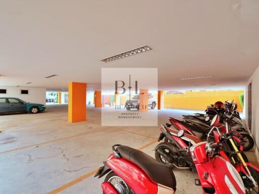 Covered parking area with multiple motorcycles and a car parked