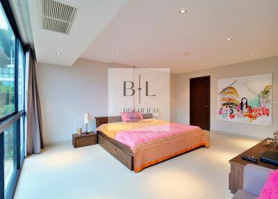 Spacious bedroom with large window, wooden bed, and colorful artwork