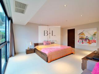 Spacious bedroom with large window, wooden bed, and colorful artwork