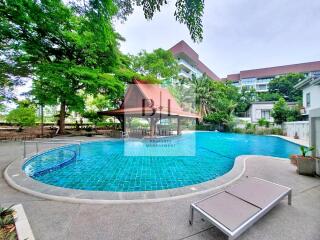 Outdoor swimming pool with surrounding greenery and buildings