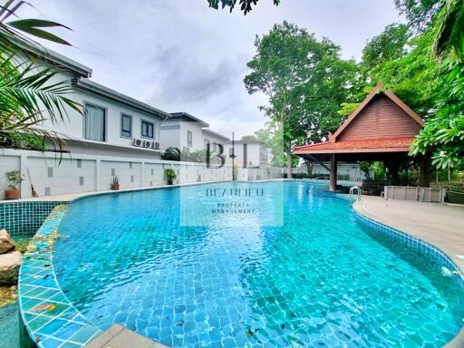 Swimming pool area with surrounding greenery and buildings