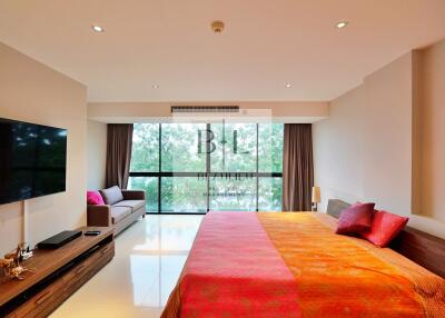 Large modern bedroom with floor-to-ceiling windows, a comfortable bed, and a wall-mounted TV