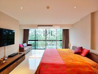 Large modern bedroom with floor-to-ceiling windows, a comfortable bed, and a wall-mounted TV