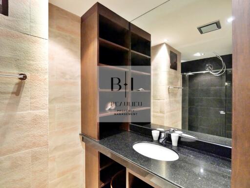 Modern bathroom with a large mirror, wooden shelving, and a sleek black countertop