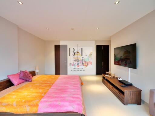 Spacious bedroom with large bed, wall-mounted TV, and modern decor