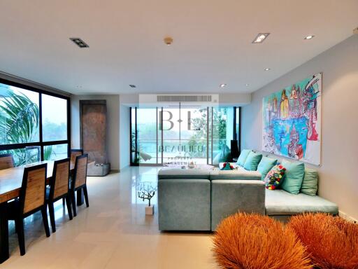 Modern living room with large windows, open dining area, and colorful decor