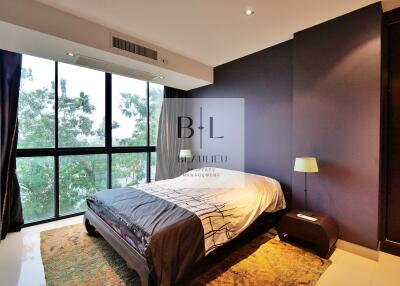 Bedroom with large window, bed, side table with lamp