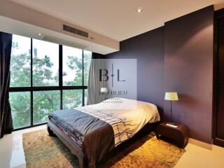 Bedroom with large window, bed, side table with lamp