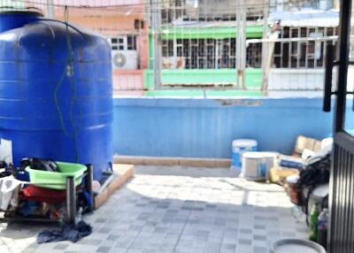 Spacious balcony with a blue water tank and overhead shelter