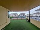 Spacious balcony with artificial grass flooring and a view of neighboring houses