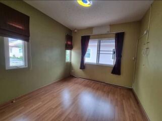 Empty bedroom with wooden flooring, windows, and ceiling fixture