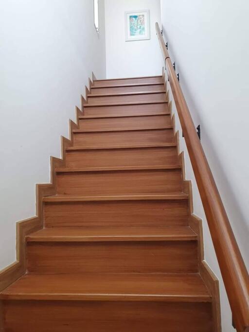 Wooden staircase with handrail in a well-lit hallway