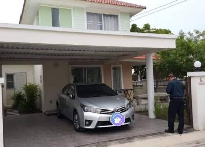 Front view of a residential property with a carport and a man standing on the driveway