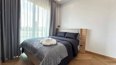 Bedroom with bed, large window with curtains, and wooden floor