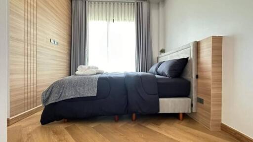 Modern bedroom with wooden flooring and cozy bed near a window