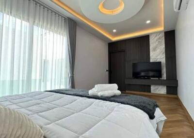 Modern bedroom with a large bed, TV, and stylish ceiling lighting