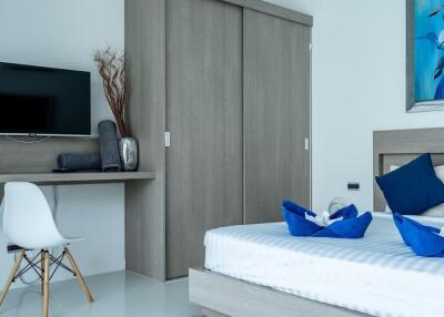 Modern bedroom with a wall-mounted TV, workspace, and stylish decor